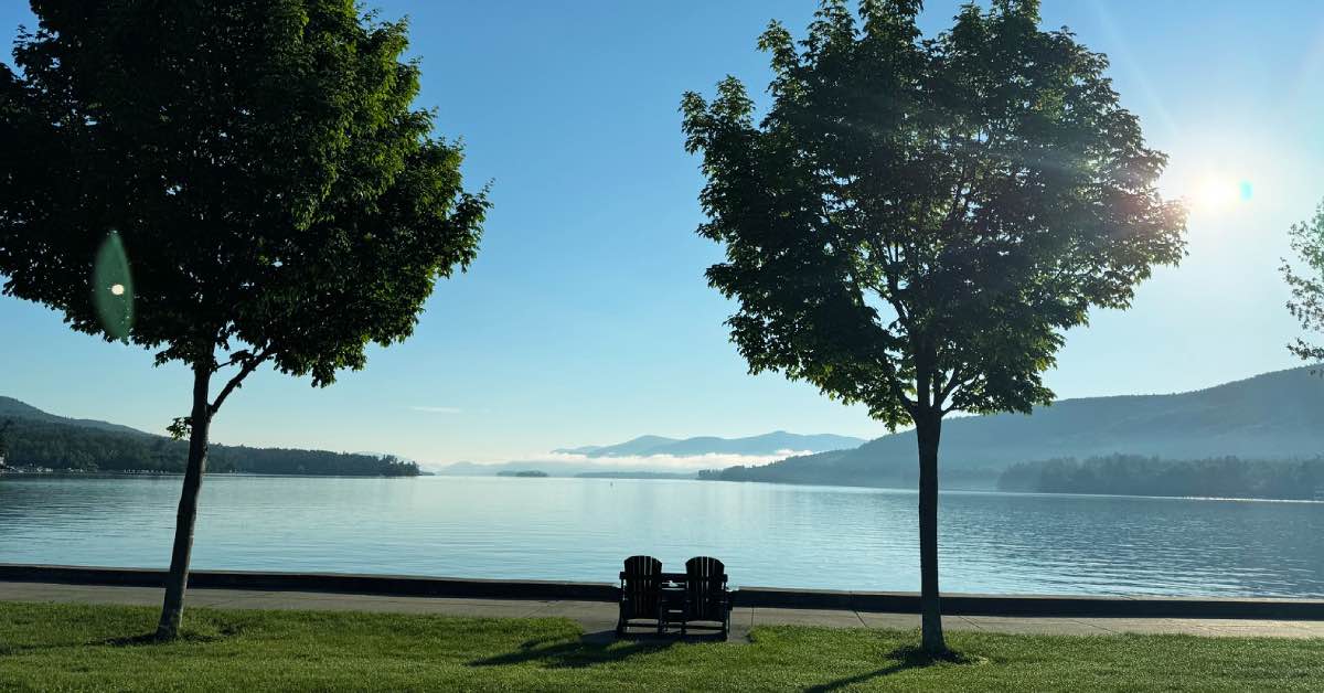 Image of Lake George with two chairs and trees by the shoreline