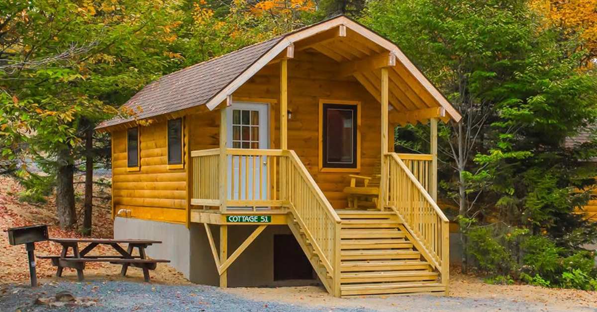 a wooden cabin with picnic table and grill outside of it