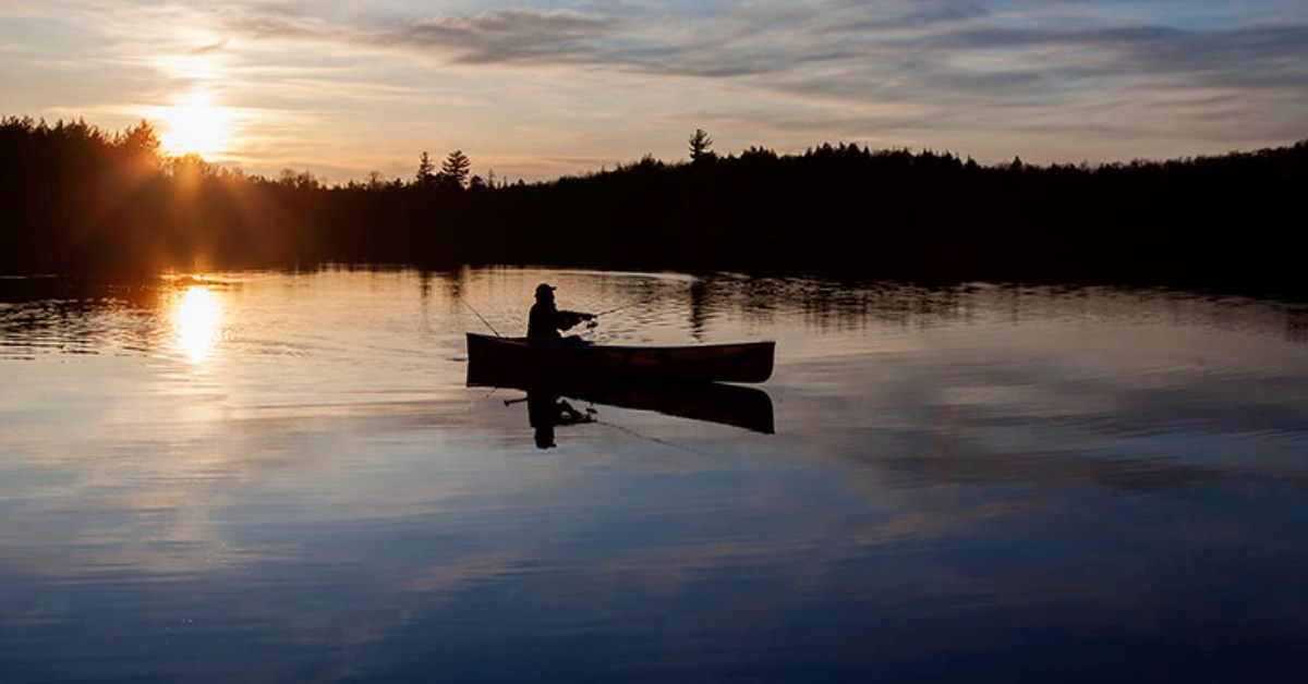 a fisherman in a canoe on a lake