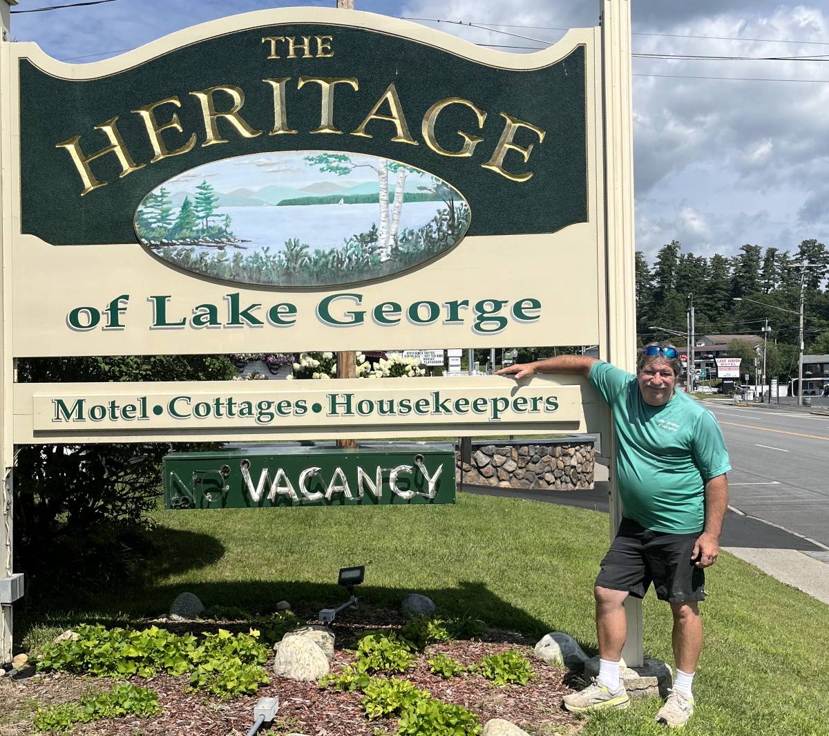 man poses with heritage of lake george sign