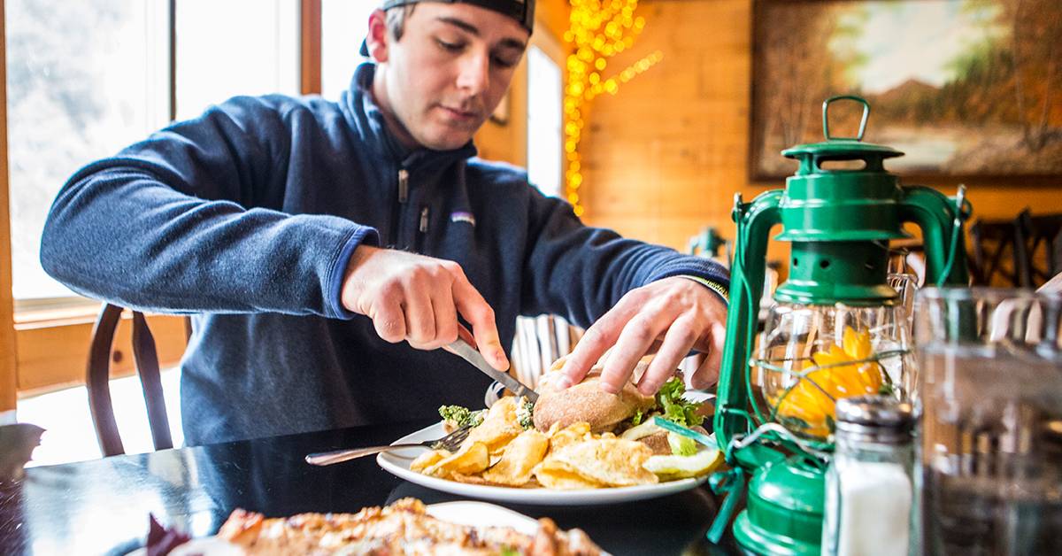 man cutting sandwich at cafe