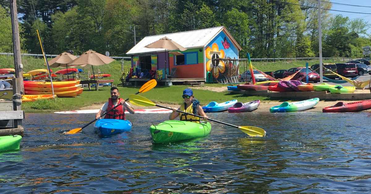 a man and woman kayaking from the shoreline kayak outfitter building