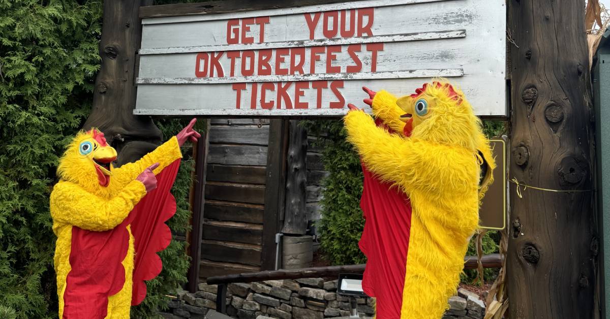 people in chicken suits pointing at sign that says get your oktoberfest tickets