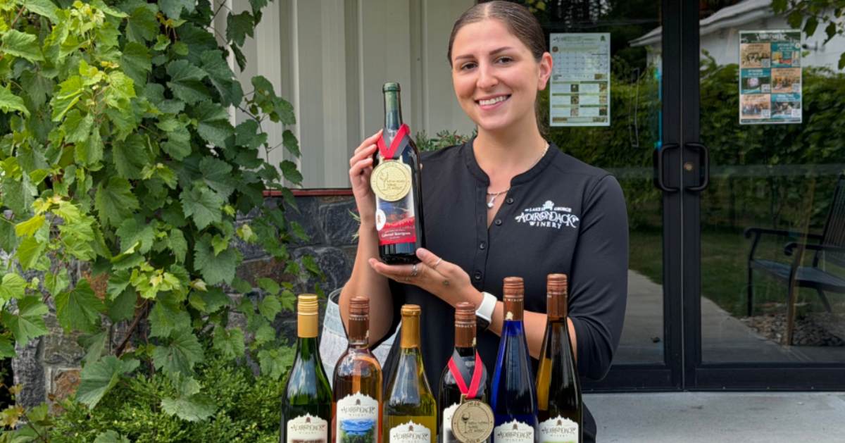 a woman holding up a bottle of wine with a medal
