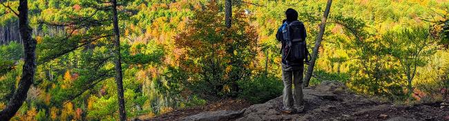 hiker with kid carrier backpack at fall summit