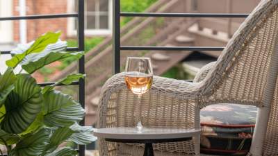 glass of white wine by plant and whicker chair looking out window