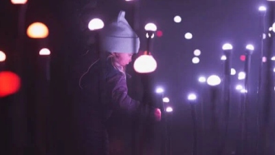 a girl standing near outdoor light displays at night