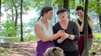 three women perform singing outdoors