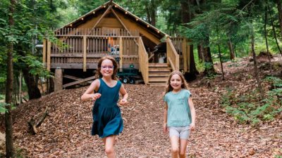 two girls in front of a cabin at huttopia adirondacks