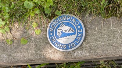 sign near sewer, no dumping drains to lake, with fish on it