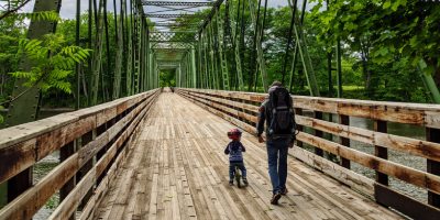 dad and kid go over bridge at hudson crossing park