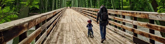 dad and kid go over bridge at hudson crossing park