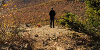 hiker and dog on mountain summit in fall