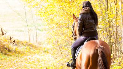 woman horseback riding in fall