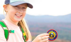 young woman holds up tupper lake triad patch