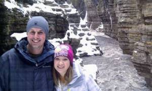 couple poses in front of winter scene in adirondacks