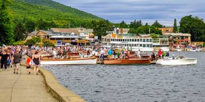 people on walkway by lake george, boats in water