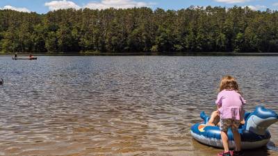 little girl with raft and other people in water at lake luzerne campground