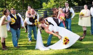 bride and groom kiss surrounded by wedding party outside