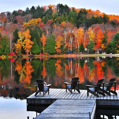 adirondack chairs on a dock with fall foliage