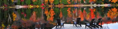 adirondack chairs on a dock with fall foliage