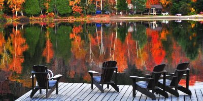 adirondack chairs on a dock with fall foliage