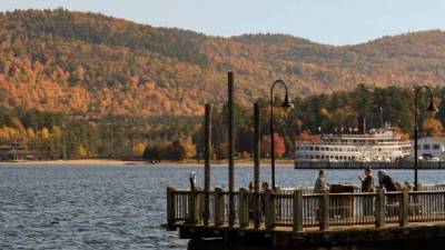 people on lake george dock looking at foliage