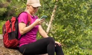 young hiker woman on summit with phone